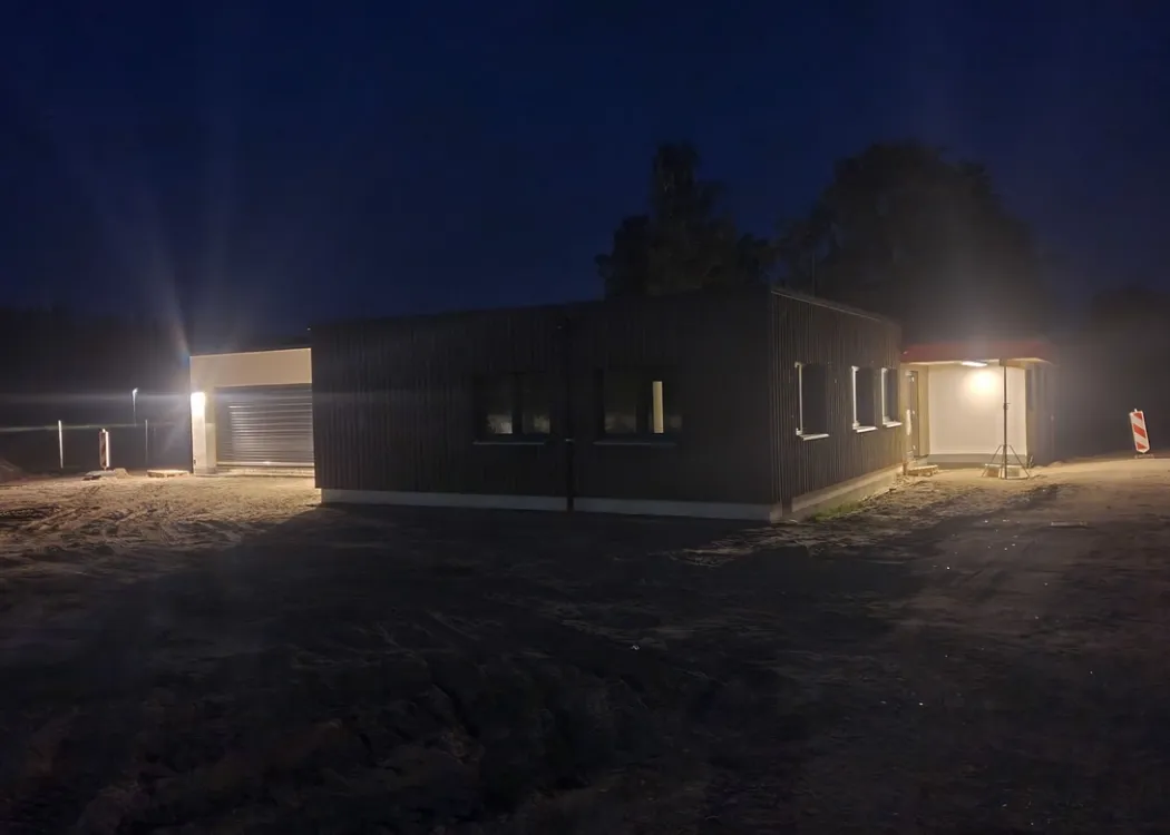 Die Tierarztpraxis Hohne im Harzklint bei Nacht. Das moderne Gebäude ist in warmem Licht von außen beleuchtet, dunkle Umgebung mit Bäumen im Hintergrund verstärkt den Kontrast.