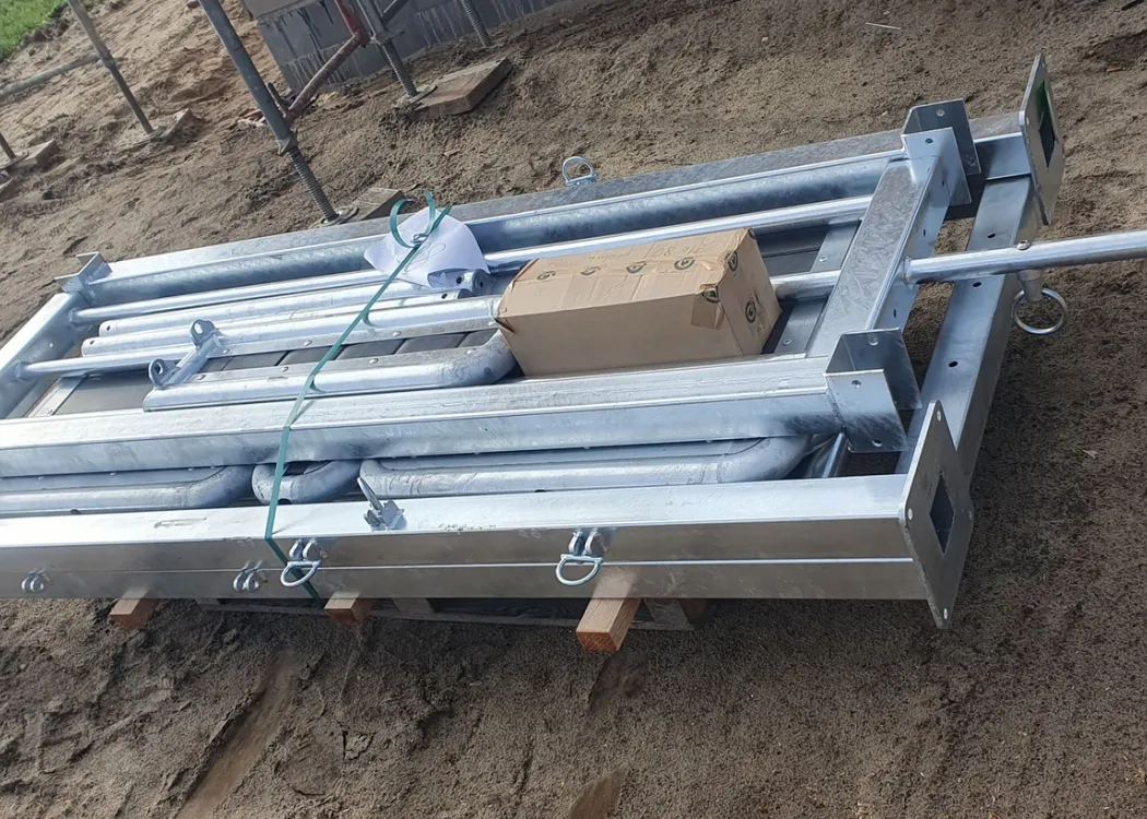 Gestapeltes Baumaterial auf der Baustelle der Tierarztpraxis Hohne im Harzklint. Mehrere große Metallrahmen und Konstruktionselemente liegen ordentlich auf einem Holzgestell auf der Erde.