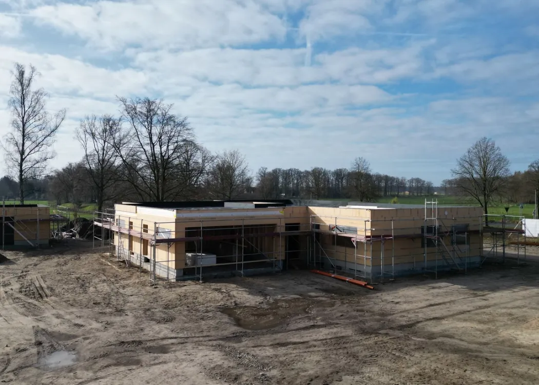 Außenansicht des Rohbaus der Tierarztpraxis Hohne im Harzklint. Ein modernes Flachdachgebäude im Bau, Holzverschalung sichtbar, umgeben von unbefestigtem Erdreich und kahlen Bäumen im Hintergrund.