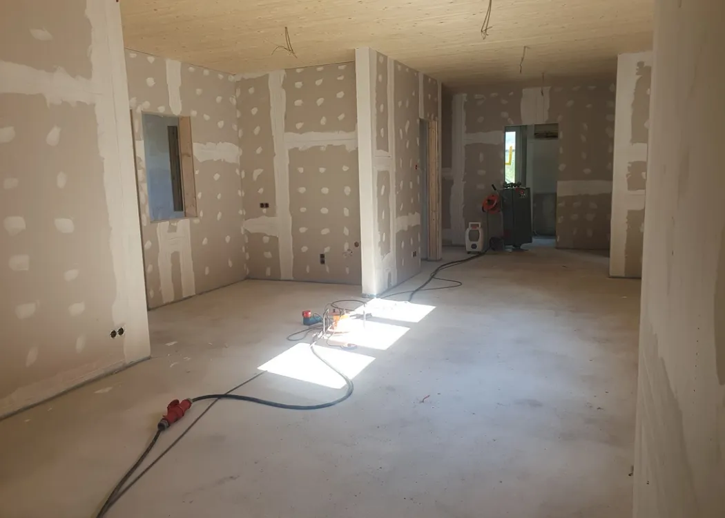 Innenaufnahme der Tierarztpraxis Hohne im Harzklint während des Ausbaus. Unverputzte Wände mit gespachtelten Gipskartonplatten, Kabel liegen lose auf dem Boden, Tageslicht fällt durch die Fenster in den unfertigen Raum.