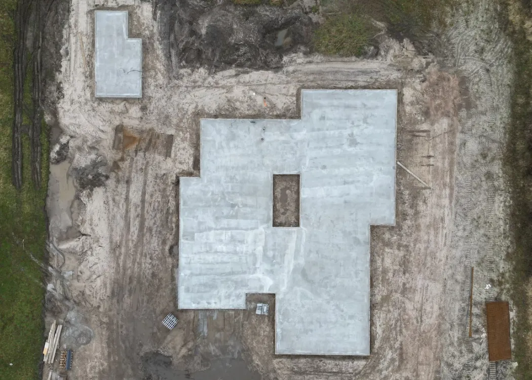 Luftaufnahme des Baugrundstücks der Tierarztpraxis Hohne im Harzklint. Sichtbar ist eine frisch gegossene Betonbodenplatte in rechteckiger Grundform mit mehreren Aussparungen für Leitungen und Räume.