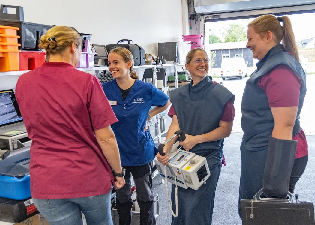 Drei Tierärztinnen und eine Tierarzthelferin stehen gemeinsam in der Praxis und lachen herzlich miteinander – Teamarbeit und Freude in der Tierarztpraxis.