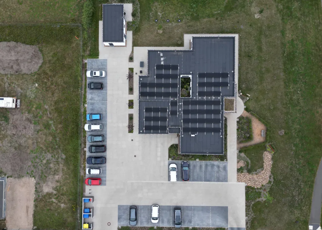 Drohnenaufnahme der Tierarztpraxis von oben mit klar erkennbarer Dachfläche, zahlreichen Solarpaneelen und großem Parkplatz.