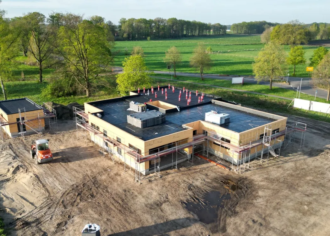 Luftbild der Tierarztpraxis Hohne im Harzklint während der Bauphase. Das Gebäude ist im Rohbauzustand, umgeben von grünen Wiesen und Bäumen, Baugeräte und Baumaterialien liegen auf dem Gelände verteilt.