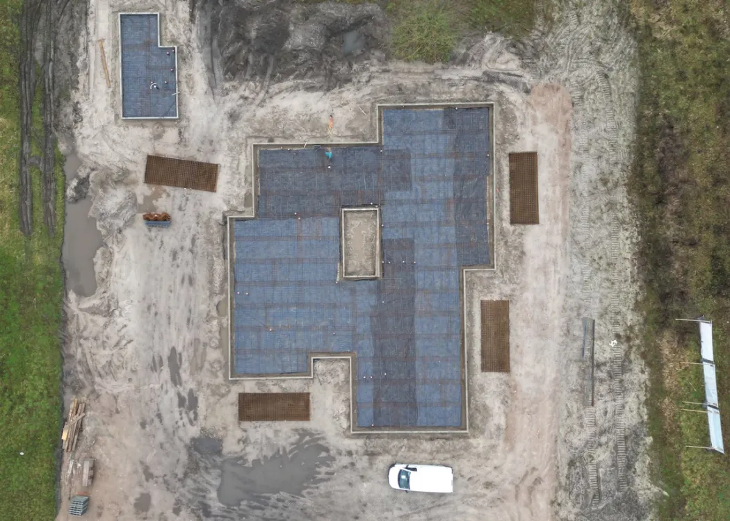 Luftaufnahme des Rohbaus der Tierarztpraxis Hohne im Harzklint. Auf der Bodenplatte sind bereits dunkle Schutzfolien oder Abdichtungen ausgelegt, die den Umriss des Gebäudes sichtbar machen.