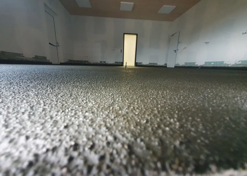 Bodennaher Blick in einen noch leeren Praxisraum der Tierarztpraxis Hohne im Harzklint. Betonboden mit Antirutschbeschichtung, Wände verputzt, im Hintergrund ein heller Raum mit geöffneter Tür.