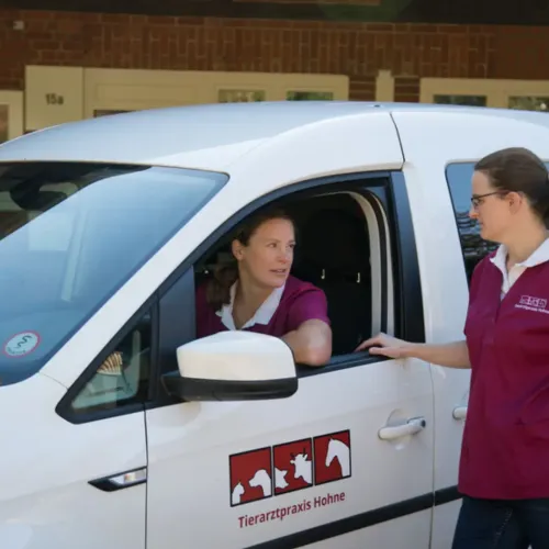 Zwei Personen in Kleidung mit Logo von Tierarztpraxis Hohne neben weißem Fahrzeug mit Tierarztpraxis Hohne Logo